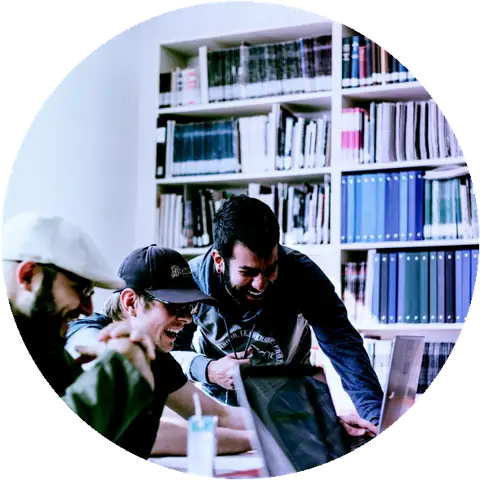 Three people looking at a laptop in front of bookshelves
